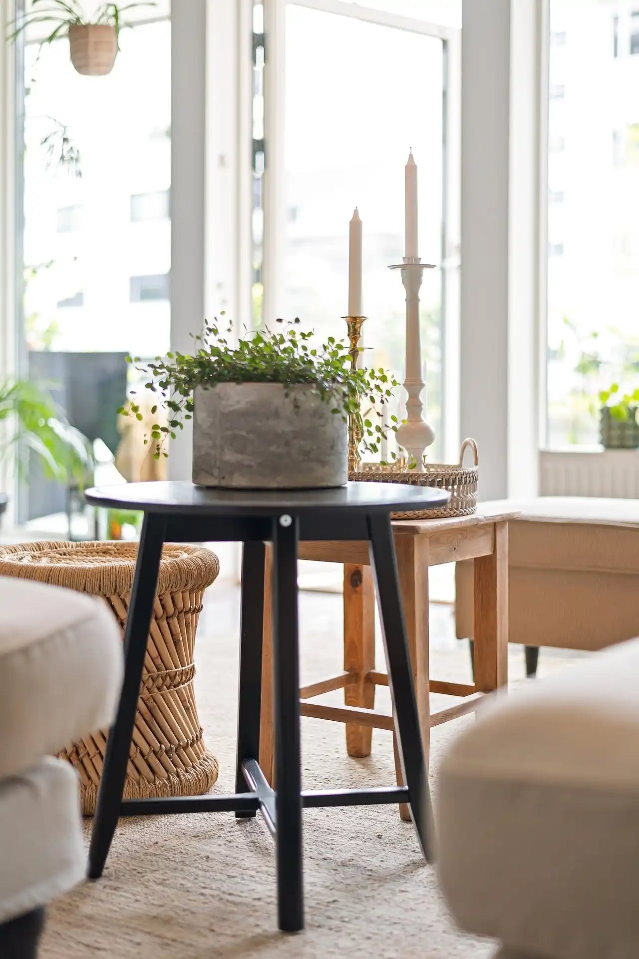 Table d'appoint en bois noir avec un pot de fleurs en béton sur le dessus.